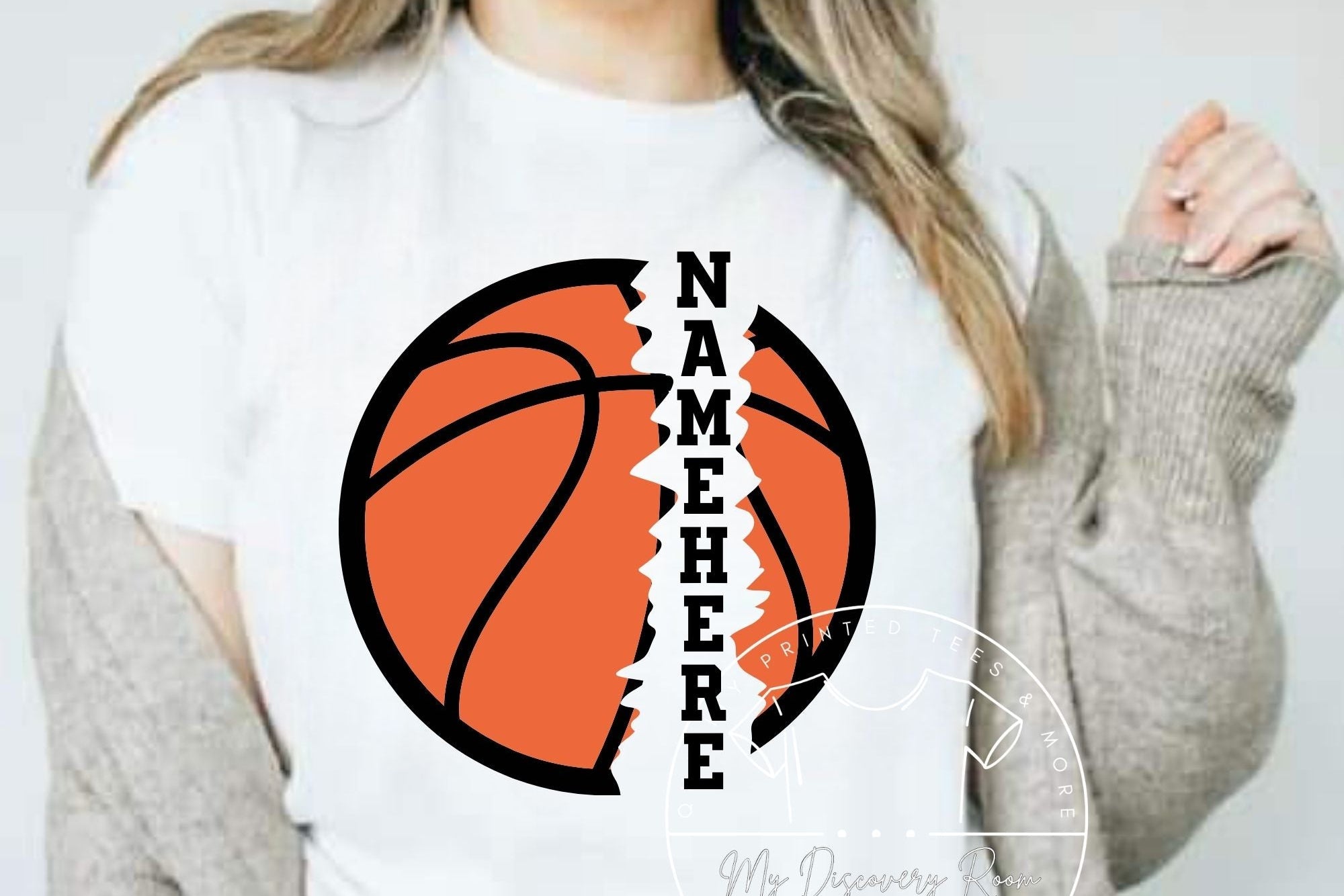 A woman wearing a hat and a white t-shirt with a graphic text that reads 'NAME HERE' and a basketball design.